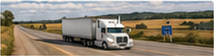 Related-article thumbnail of a white transport truck on a rural highway through prairie fields.
